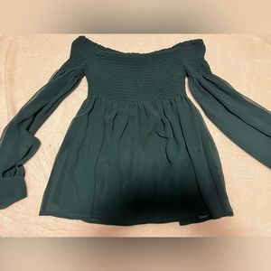 Elastic off the shoulder flowy top with sleeves. The color is emerald green